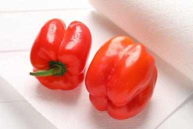 Photo of Roll of paper towels with wet bell peppers on white wooden table, closeup