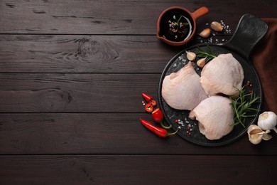 Photo of Raw chicken thighs and ingredients on wooden table, flat lay. Space for text