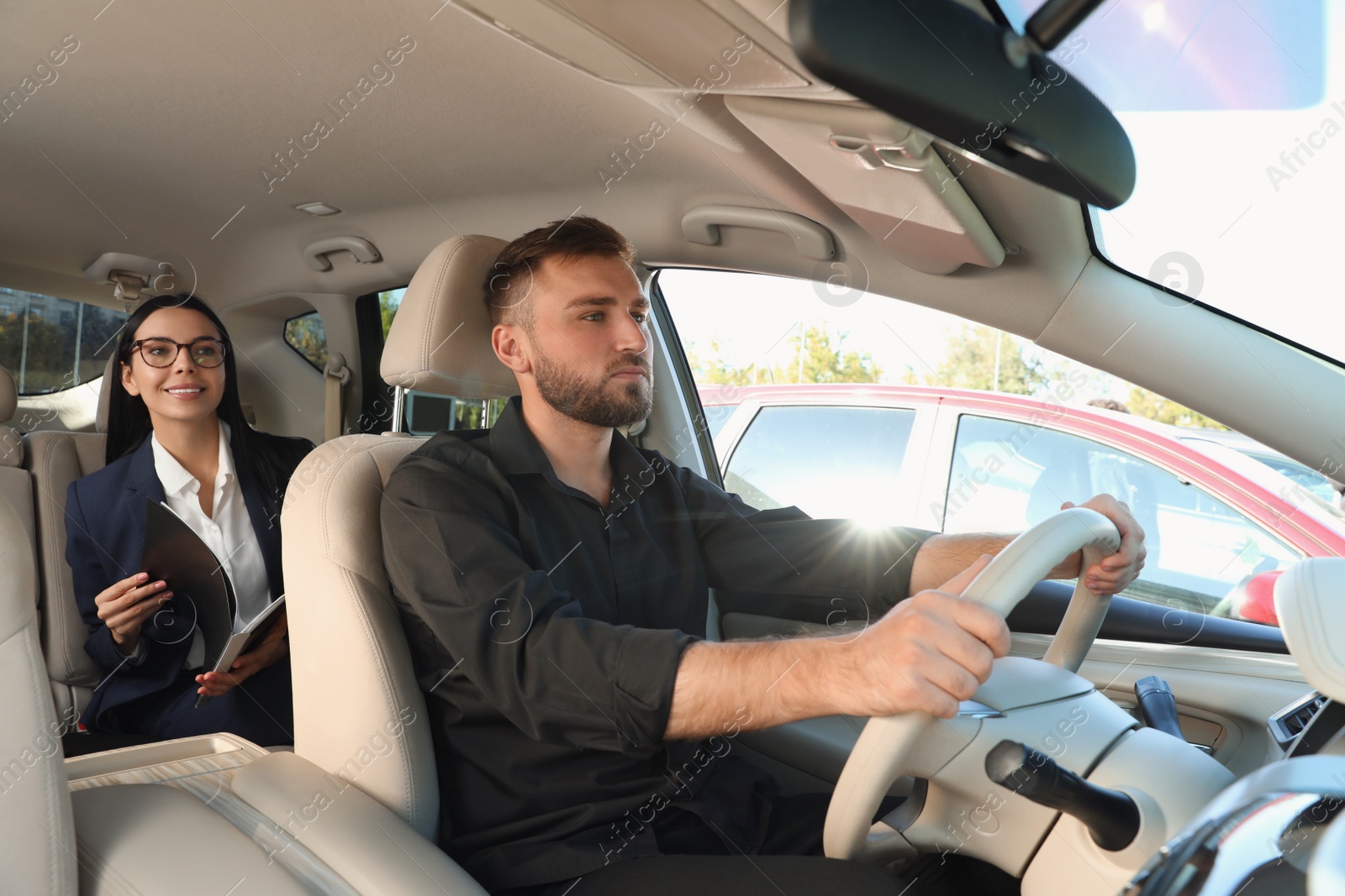 Photo of Young woman and driver in modern car