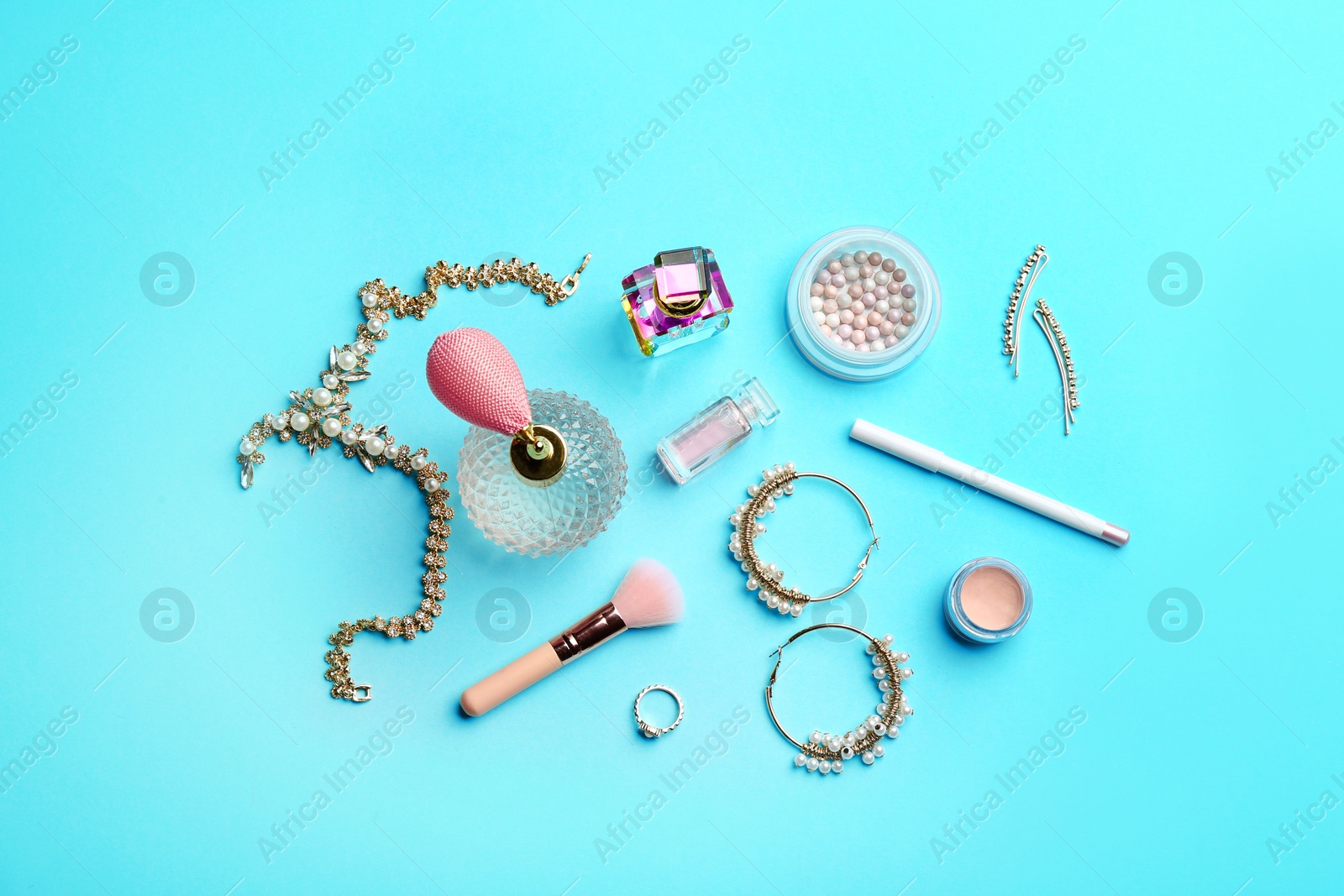 Photo of Flat lay composition with perfume bottles, jewelry and cosmetic products on blue background