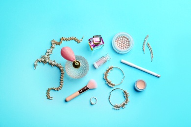 Flat lay composition with perfume bottles, jewelry and cosmetic products on blue background