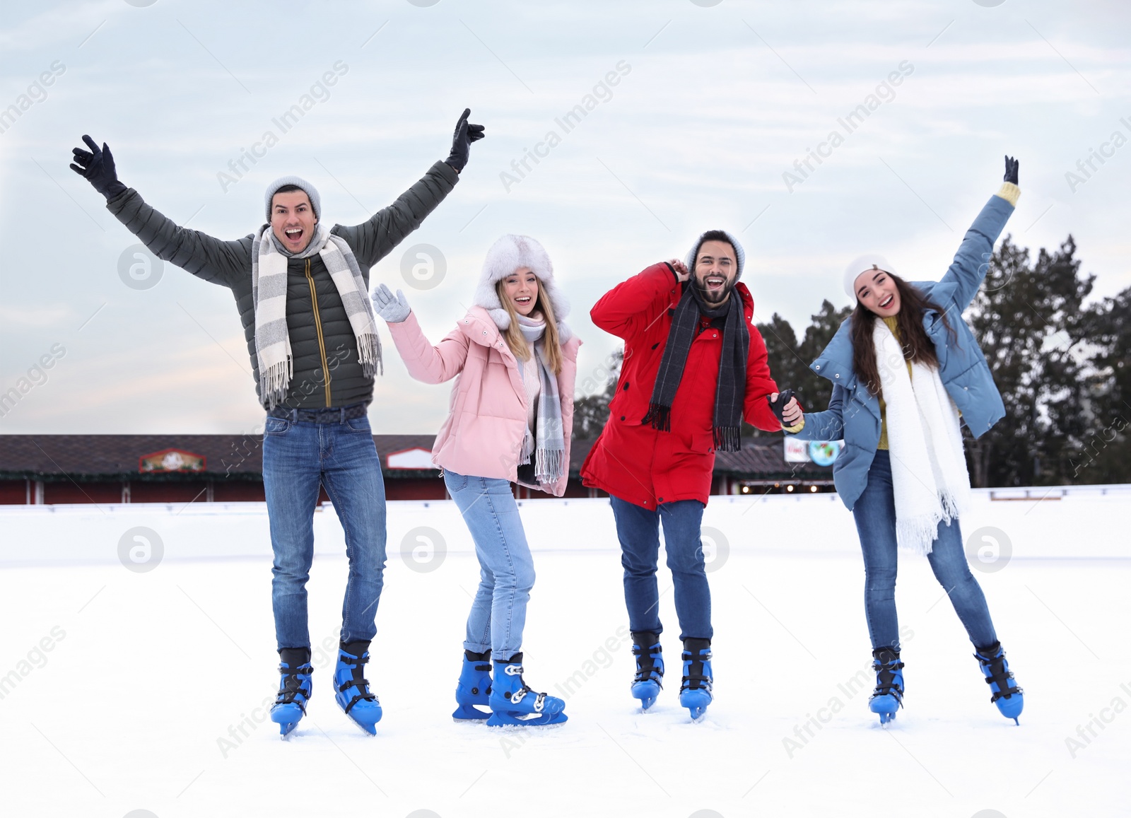 Image of Happy friends skating along ice rink outdoors