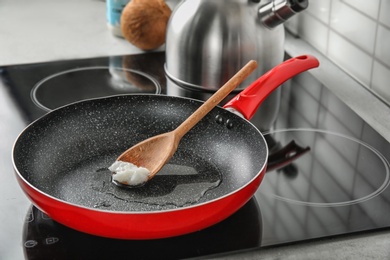 Wooden spoon with coconut oil in frying pan. Healthy cooking