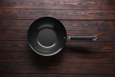 Photo of Empty iron wok on wooden table, top view. Chinese cookware