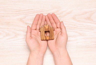 Photo of Home security concept. Man holding house model at wooden table, top view