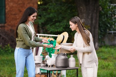 Photo of Women shopping at table in yard. Garage sale