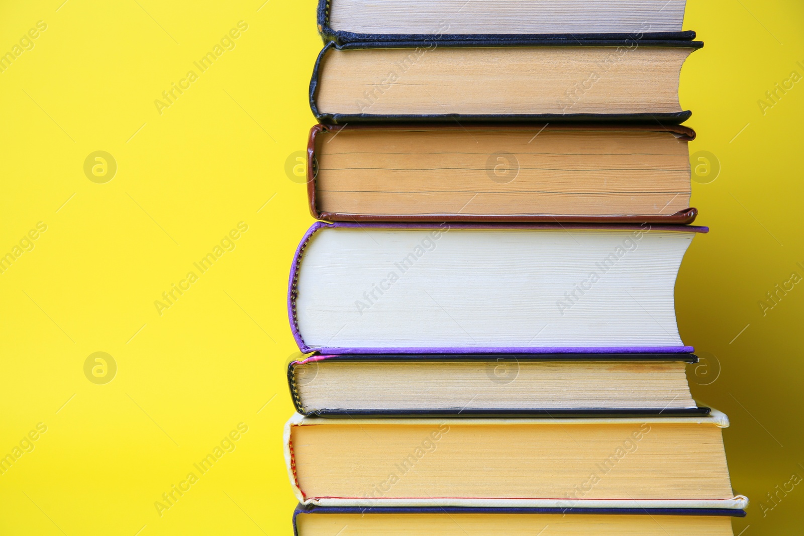 Photo of Collection of hardcover books on yellow background, space for text