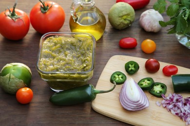 Photo of Tasty salsa sauce and ingredients on wooden table, view from above
