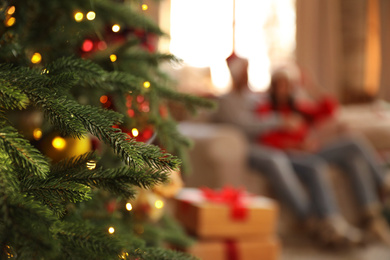 Photo of Couple on sofa indoors, focus on Christmas tree