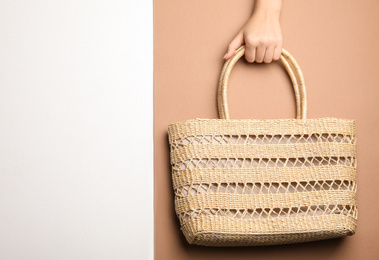 Photo of Woman holding straw bag on color background, top view. Space for text