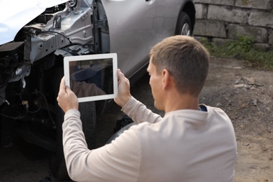 Man taking photo of broken car after accident for insurance claim