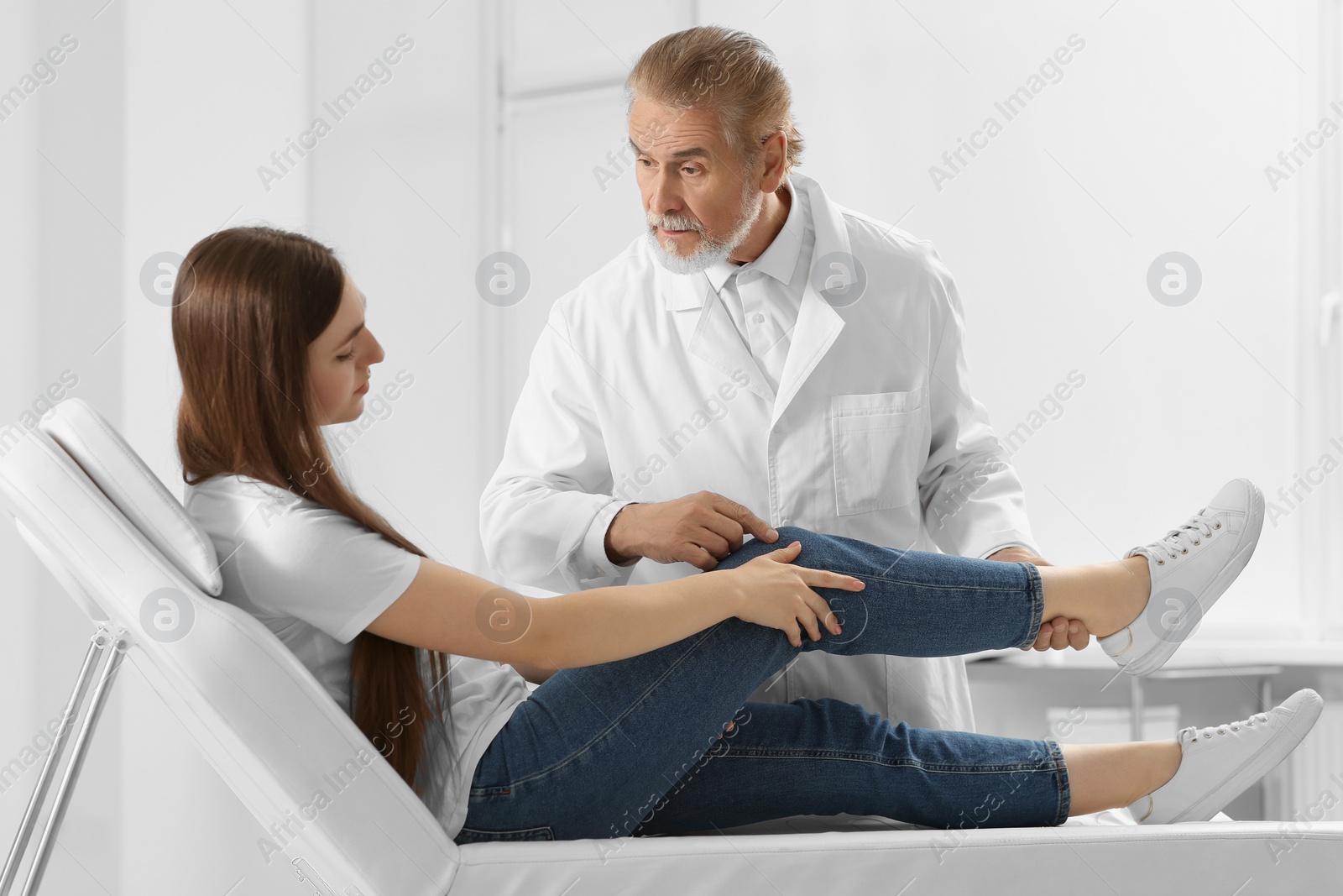 Photo of Orthopedist examining patient with injured knee in clinic