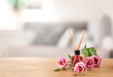 Aromatic reed air freshener and roses on table indoors