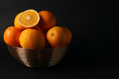 Photo of Bowl with ripe juicy oranges on black background. Space for text