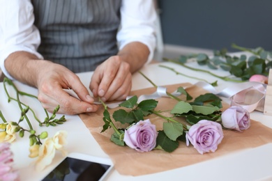 Male florist creating beautiful bouquet at table, closeup