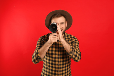 Young man using vintage video camera on red background