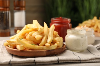 Delicious french fries served with sauces on light wooden table, closeup