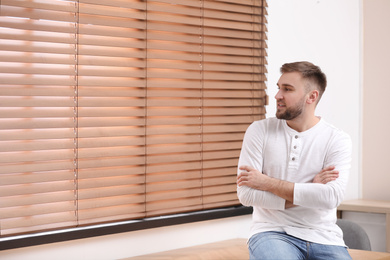 Photo of Handsome young man near window at home