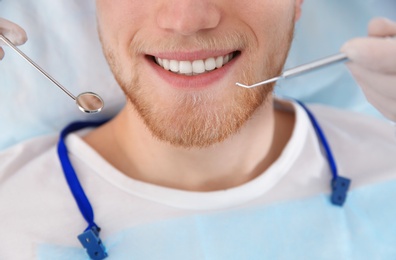 Dentist examining patient's teeth in modern clinic, closeup