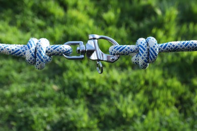 Climbing ropes with carabiner on blurred green background, closeup