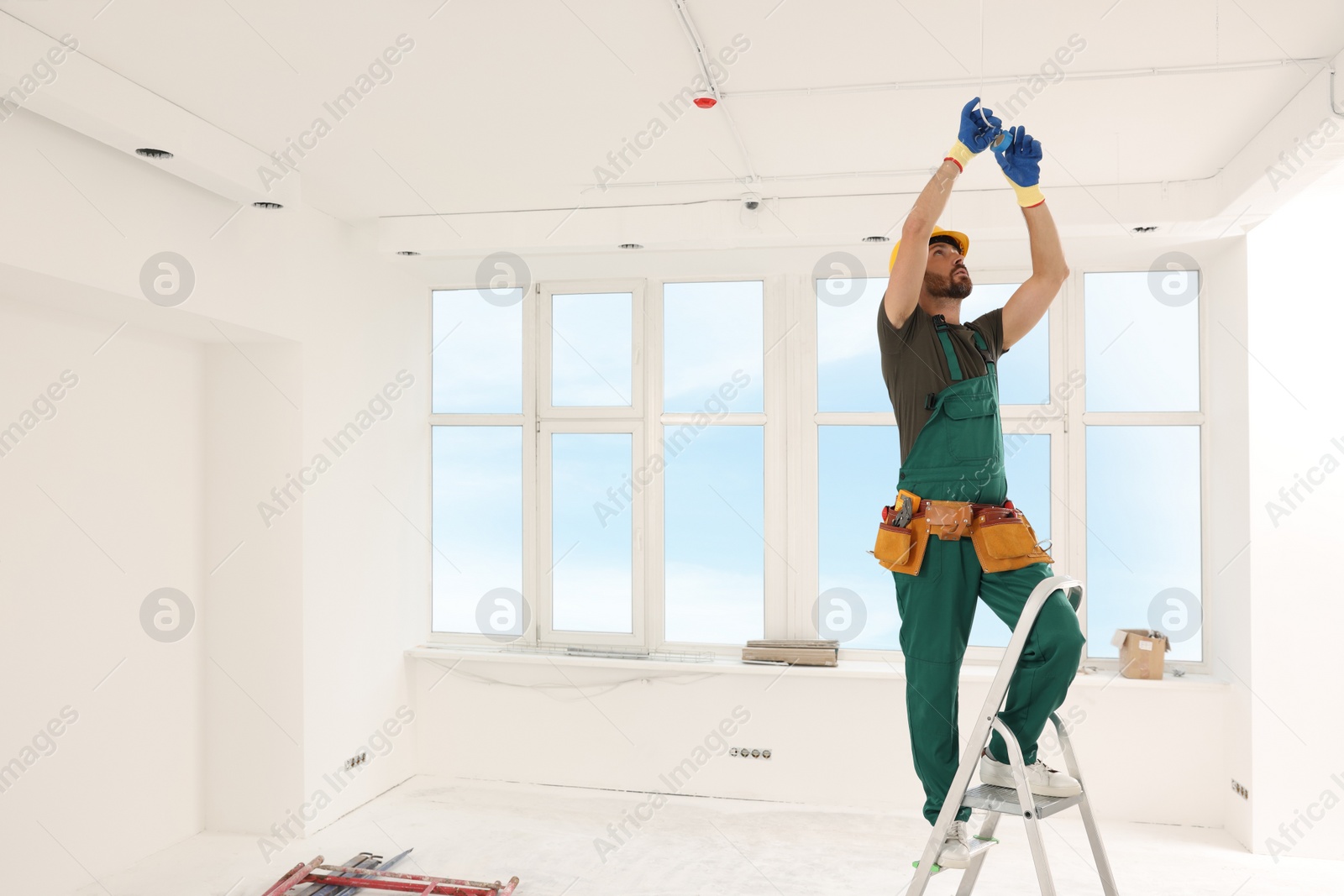 Photo of Electrician fixing wires with insulating tape indoors