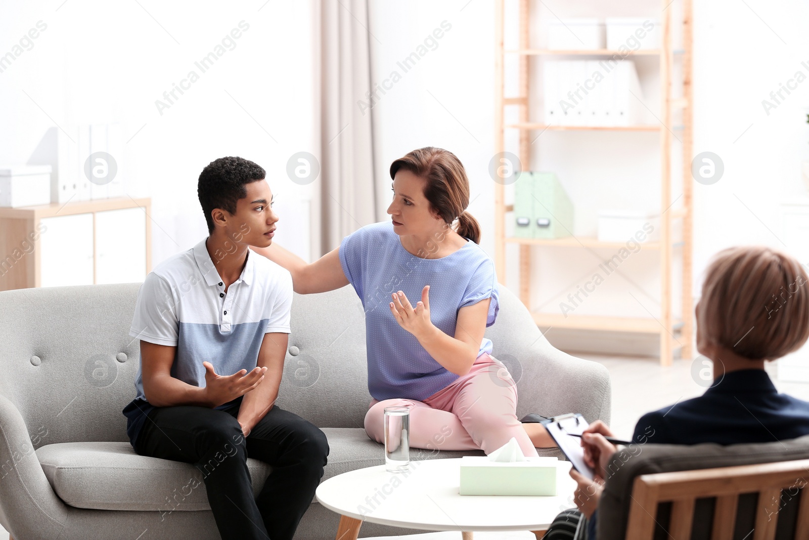 Photo of Psychotherapist working with African-American teenage boy and his mother in office
