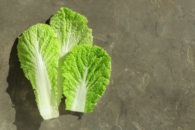 Photo of Fresh Chinese cabbage leaves on gray textured table, top view. Space for text