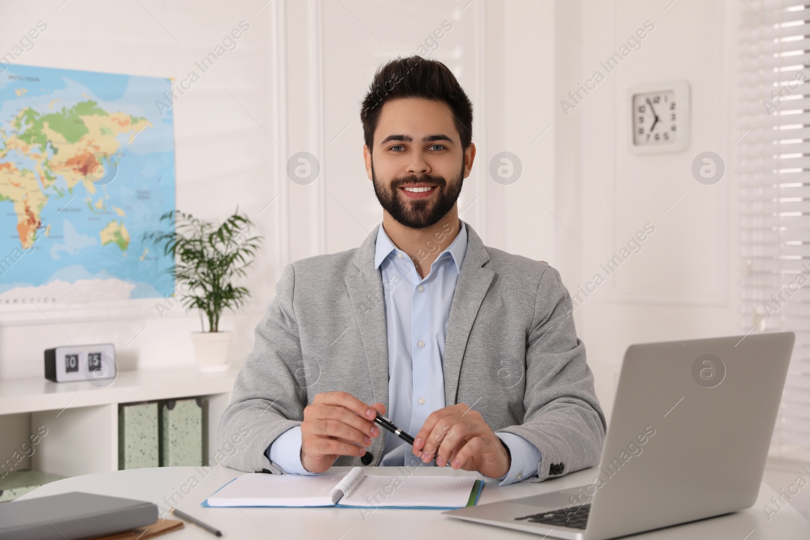 Photo of Happy manager with notebook sitting at desk in travel agency