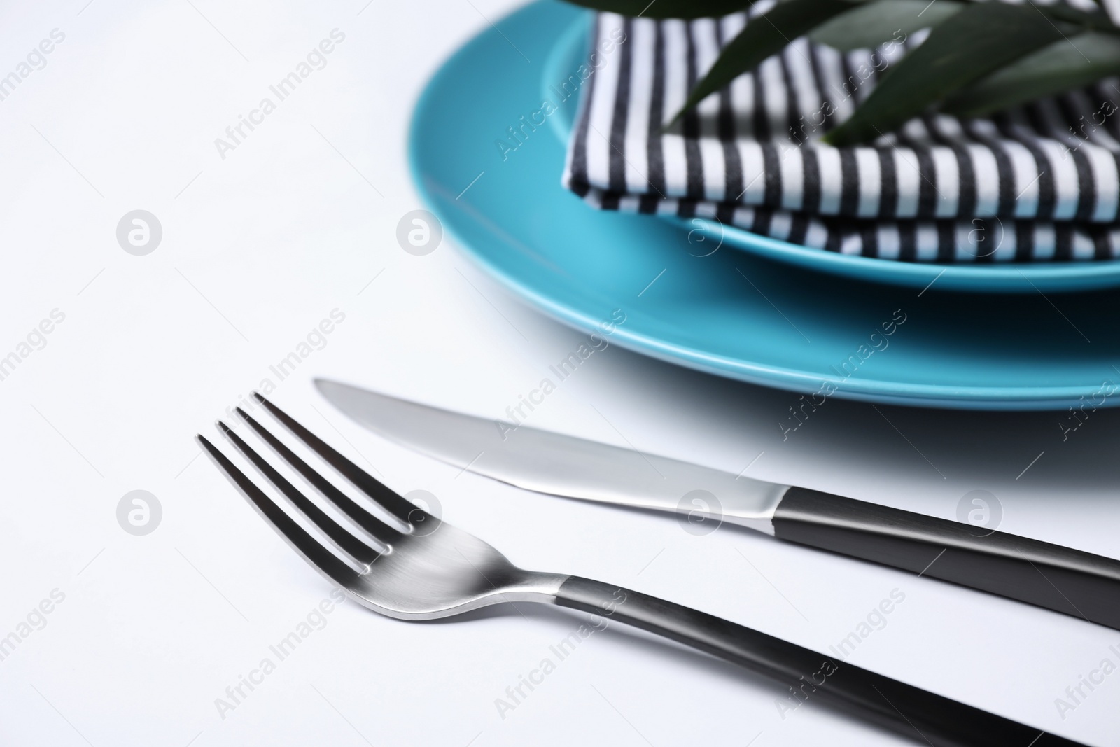 Photo of Fork and knife near plates on white background, closeup. Table setting