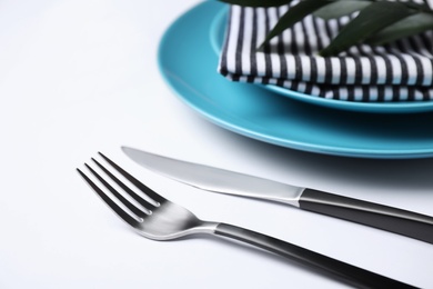 Photo of Fork and knife near plates on white background, closeup. Table setting