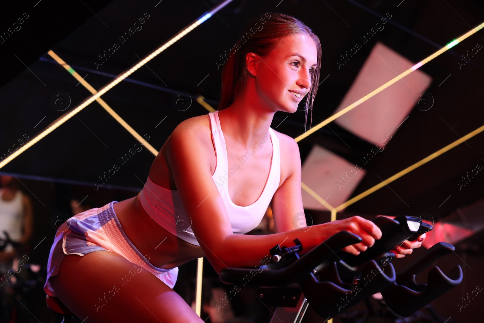 Photo of Young woman training on exercise bike in fitness club