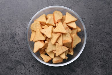 Photo of Crispy rusks in bowl on grey table, top view