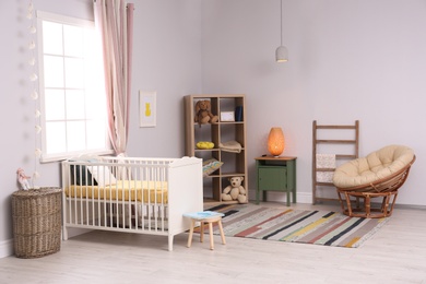 Photo of Baby room interior with comfortable crib and papasan chair