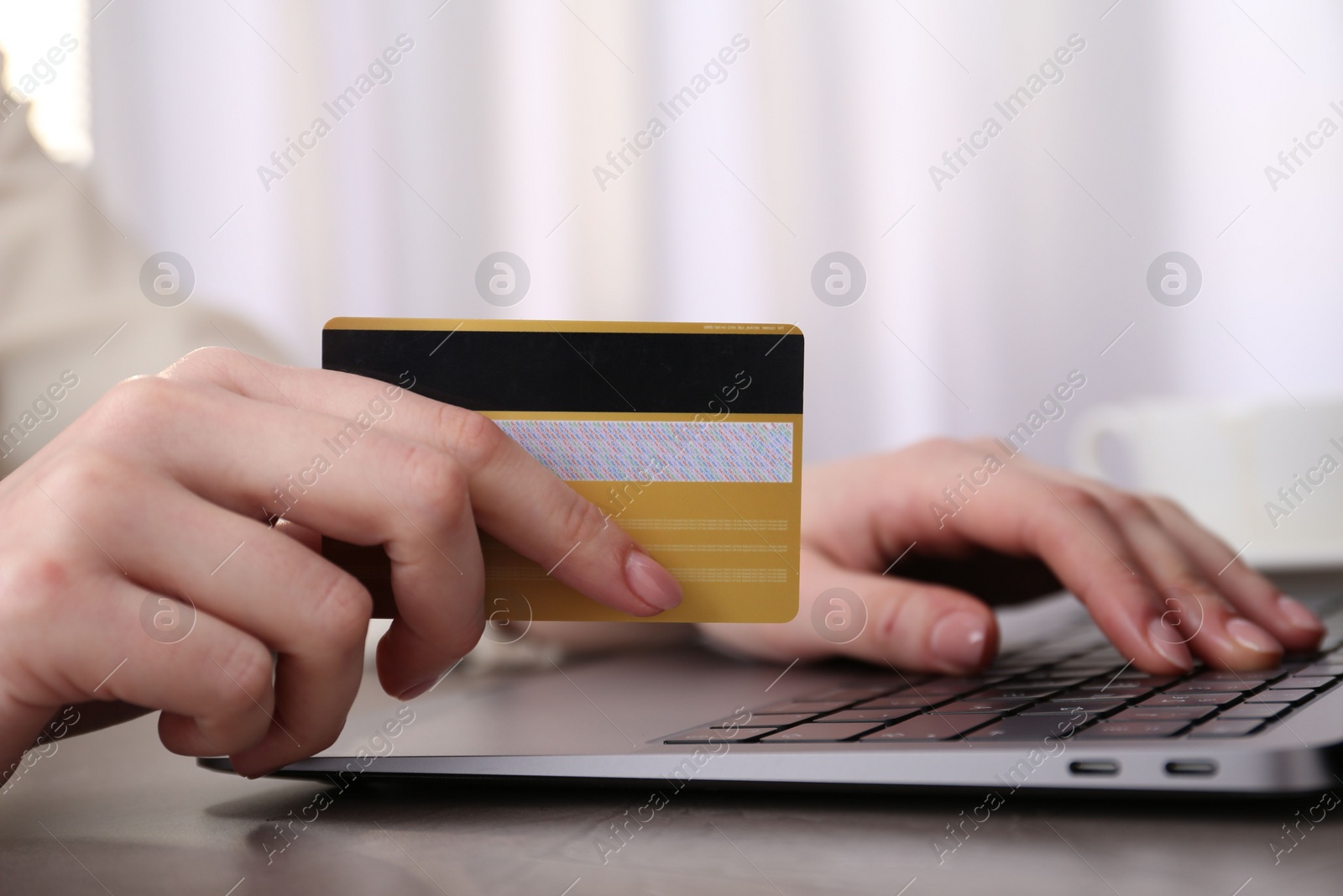 Photo of Online payment. Woman with laptop and credit card at grey table, closeup