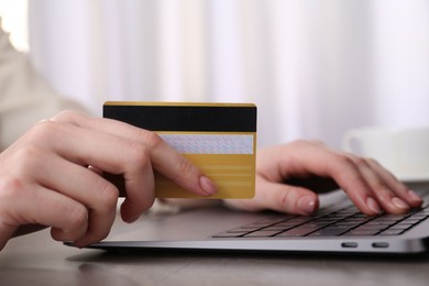 Online payment. Woman with laptop and credit card at grey table, closeup