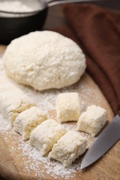 Photo of Making lazy dumplings. Raw dough, flour and knife on wooden board, closeup