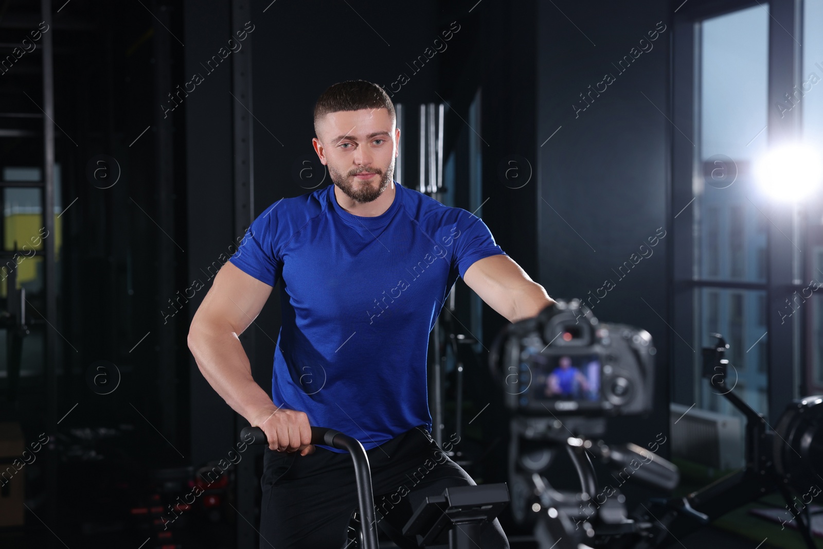 Photo of Man recording workout on camera at gym. Online fitness trainer