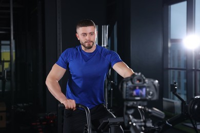 Photo of Man recording workout on camera at gym. Online fitness trainer