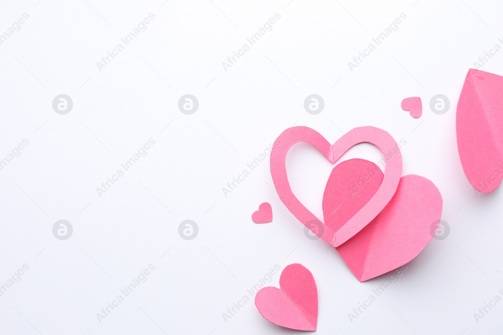 Photo of Pink paper hearts on white background, flat lay. Space for text