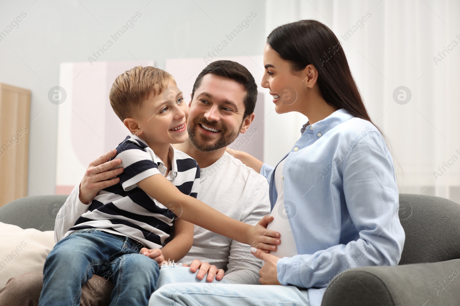 Photo of Happy pregnant woman spending time with her son and husband at home