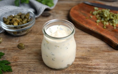 Photo of Tasty tartar sauce in glass jar on wooden table