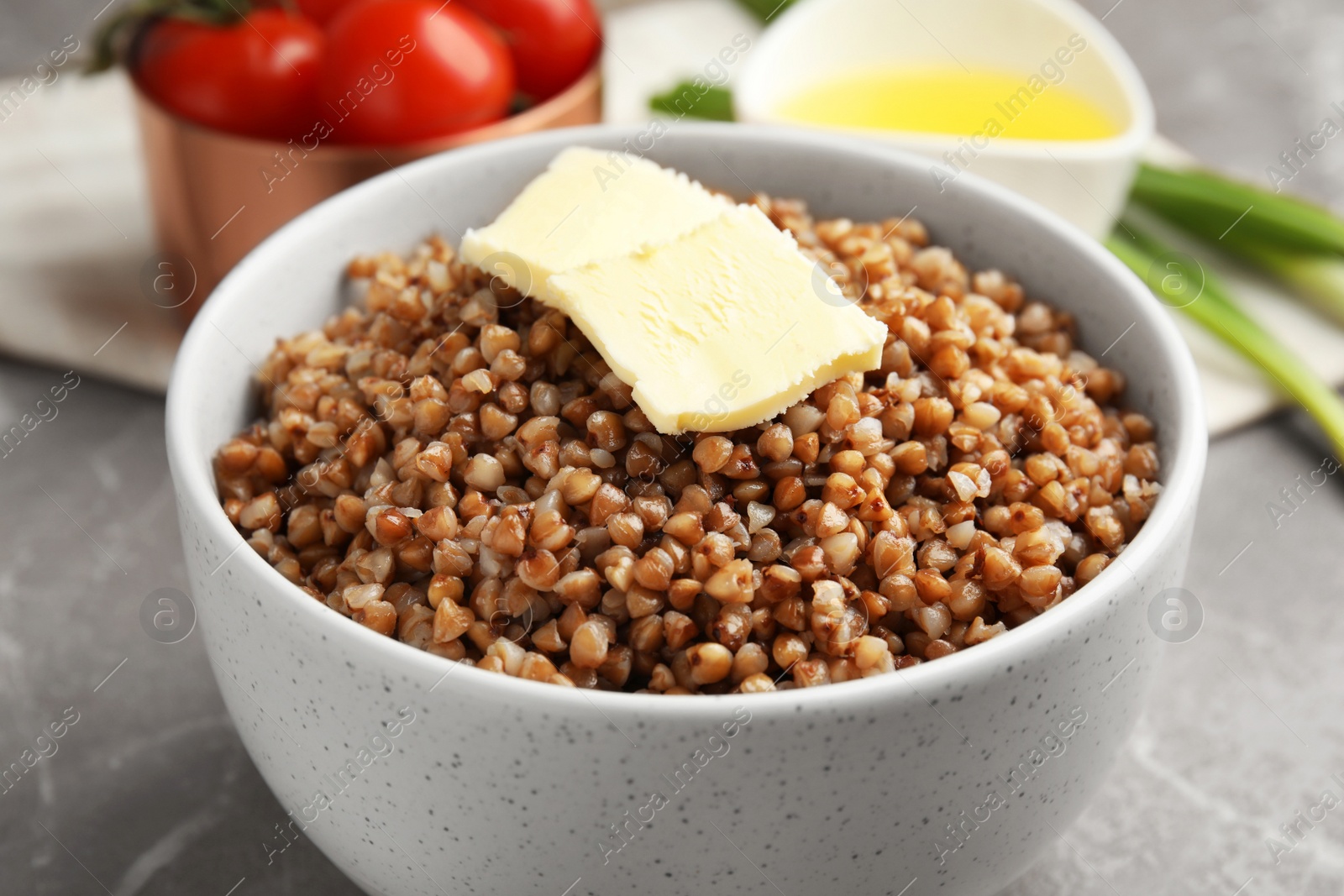 Photo of Bowl of buckwheat porridge with butter on table, closeup