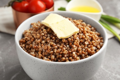 Photo of Bowl of buckwheat porridge with butter on table, closeup