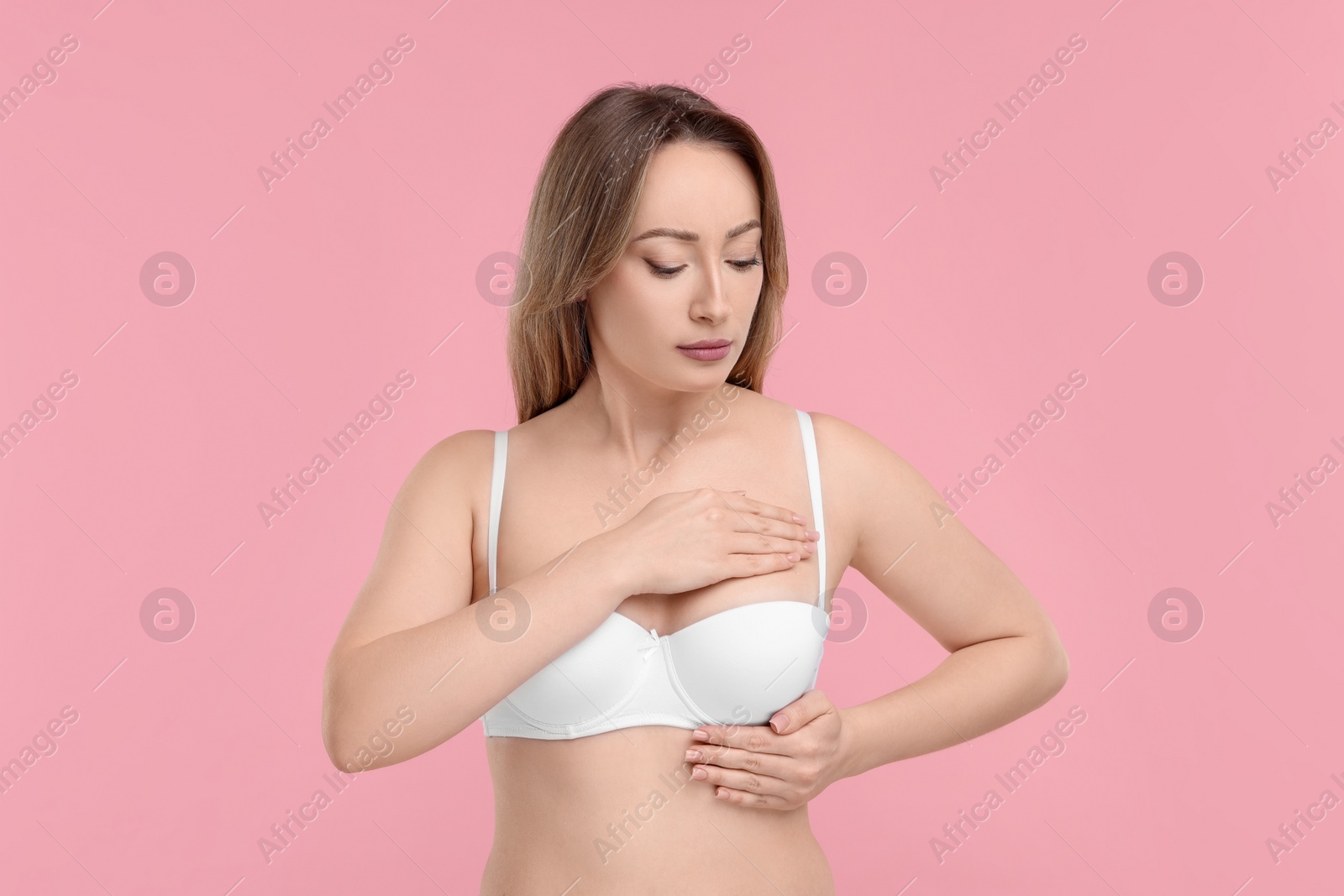 Photo of Mammology. Young woman doing breast self-examination on pink background