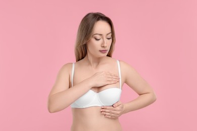 Mammology. Young woman doing breast self-examination on pink background