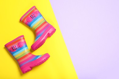 Photo of Pair of striped rubber boots on color background, top view. Space for text