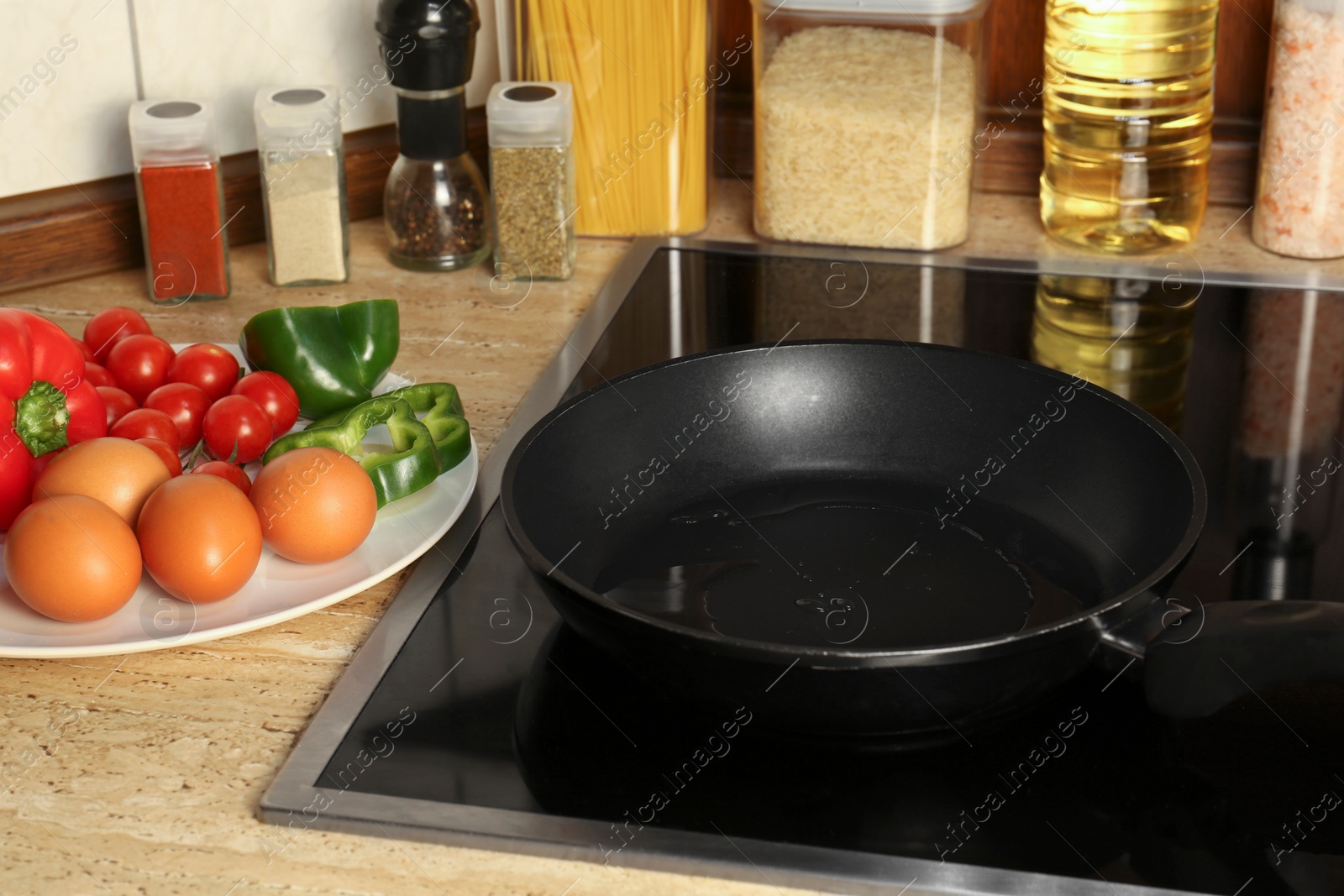 Photo of Many eggs and vegetables near frying pan on wooden countertop in kitchen