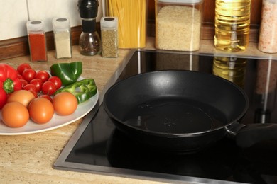 Photo of Many eggs and vegetables near frying pan on wooden countertop in kitchen