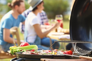 Photo of Modern grill with vegetables and blurred people on background