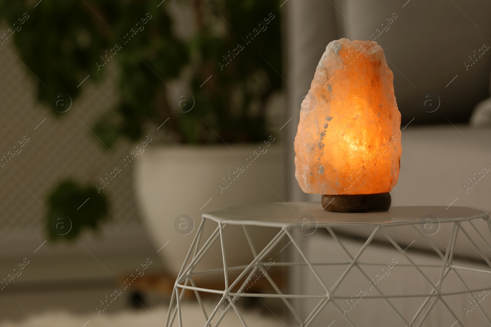 Photo of Himalayan salt lamp on table against blurred background